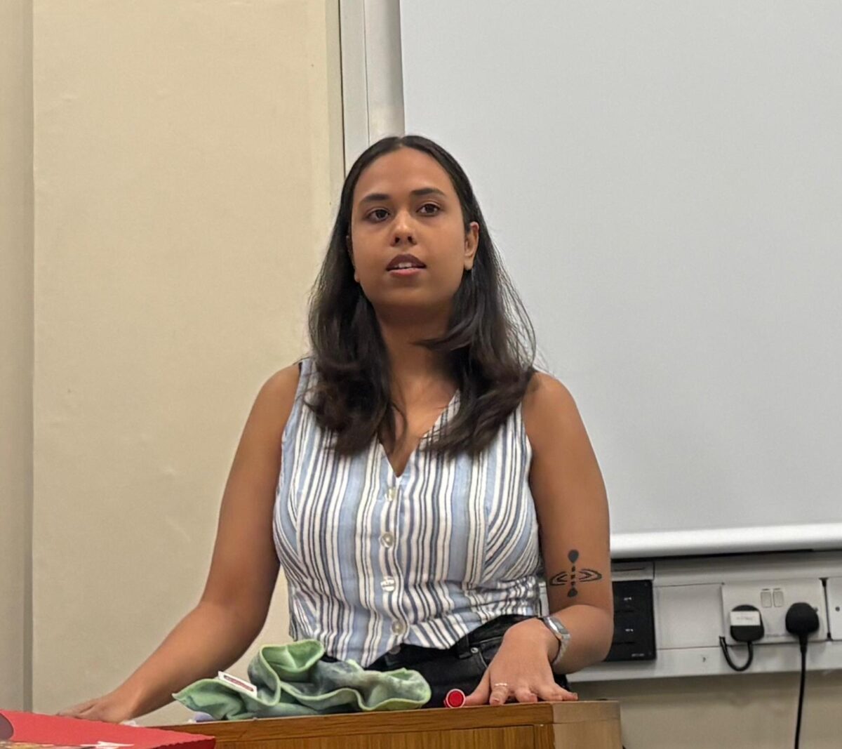 A young woman speaks standing up behind a podium for hustings.
