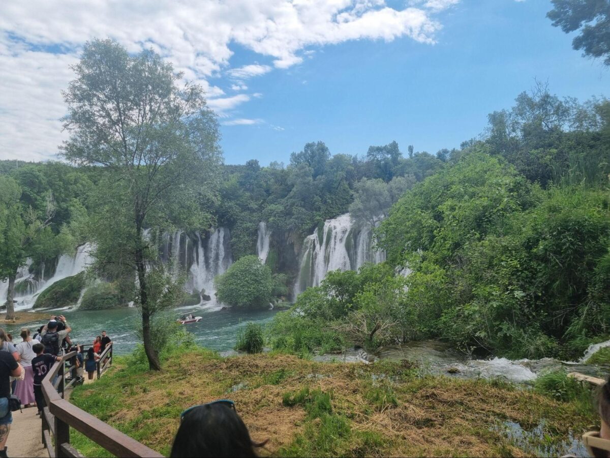 Kravice waterfalls, in Bosnia and Herzegovina pictured on a clear day. People gather to take pictures of the light blue water.