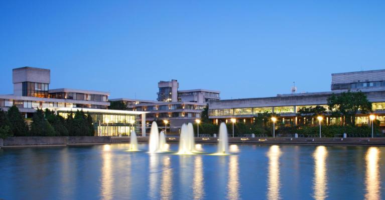 University lake at night with lit up water fountains.